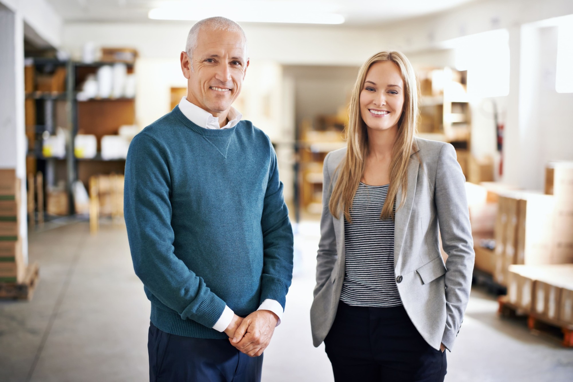 Two business owners smiling together in their warehouse