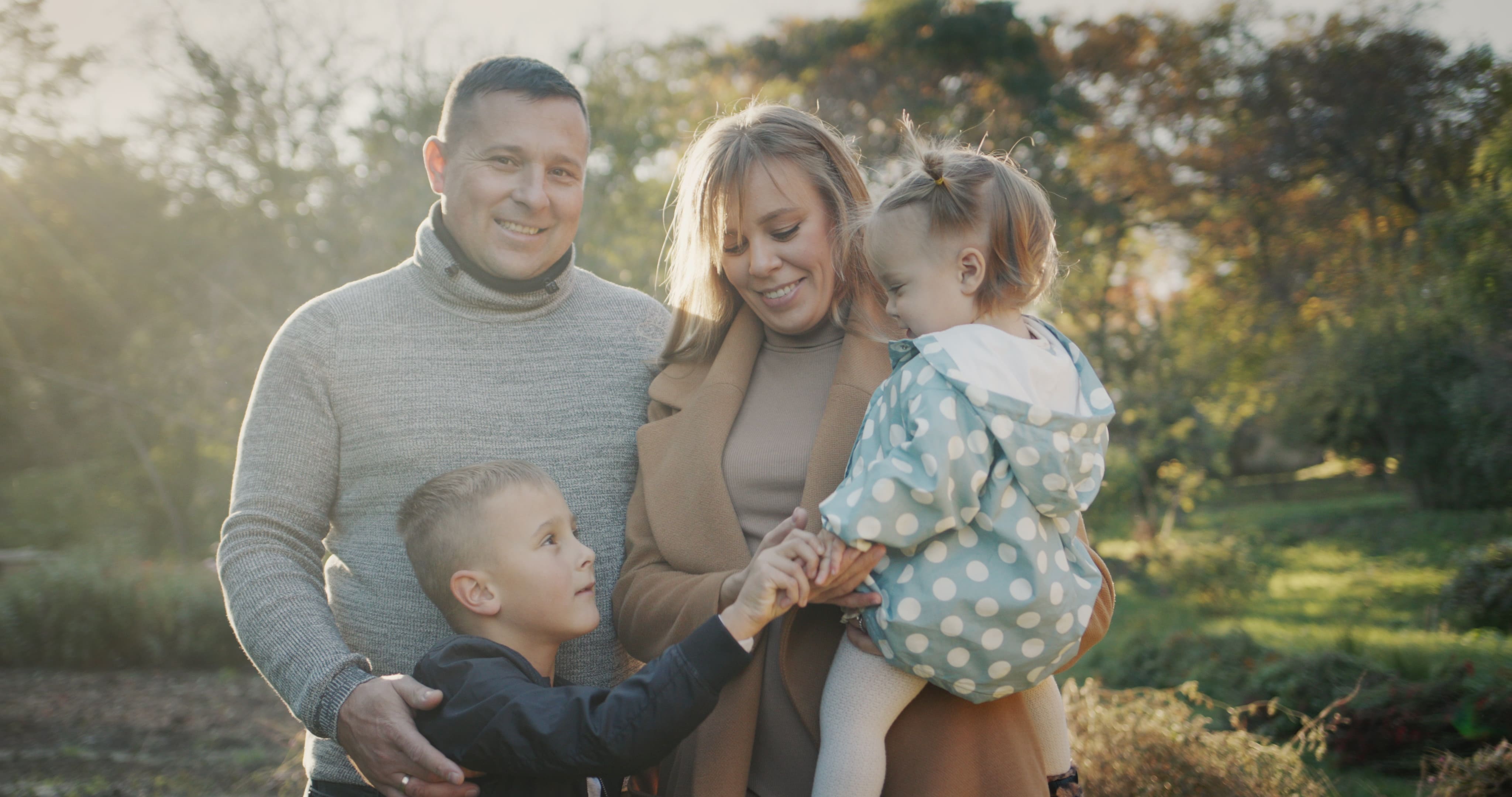 A young family smiling together in an autumn park